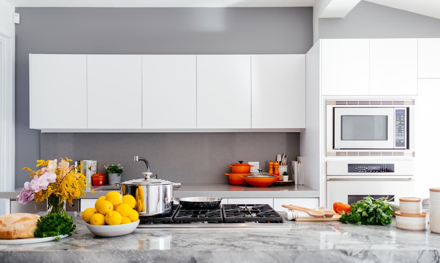 A bright modern kitchen with pale cabinets and a stone worktop