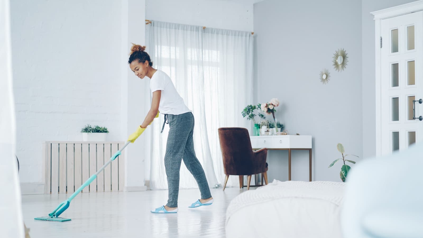 A cleaner mopping the floor of a bright, uncluttered room